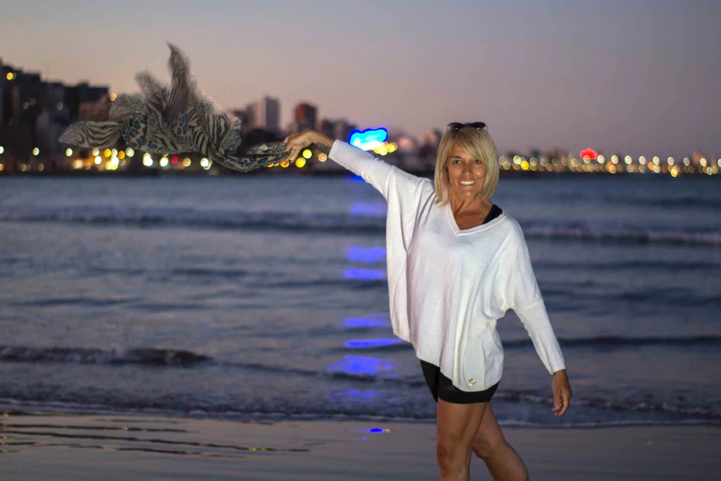 mujer con mar y ciudad iluminada de fondo